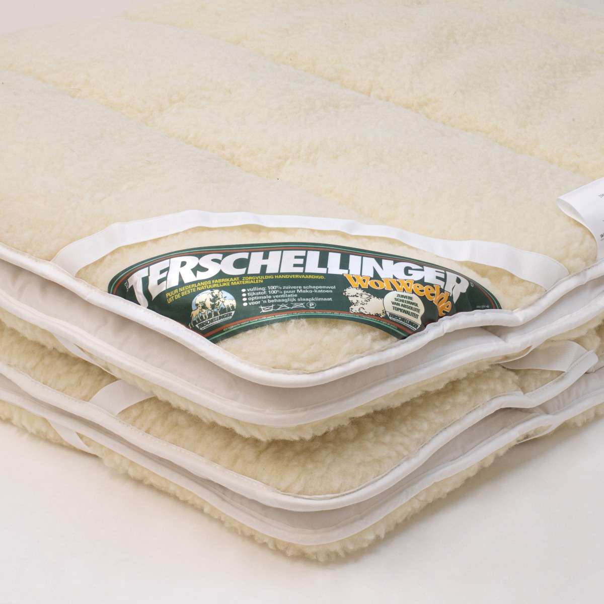 Detail van wollen beddengoed met focus op stof, afwerking en natuurlijke materialen