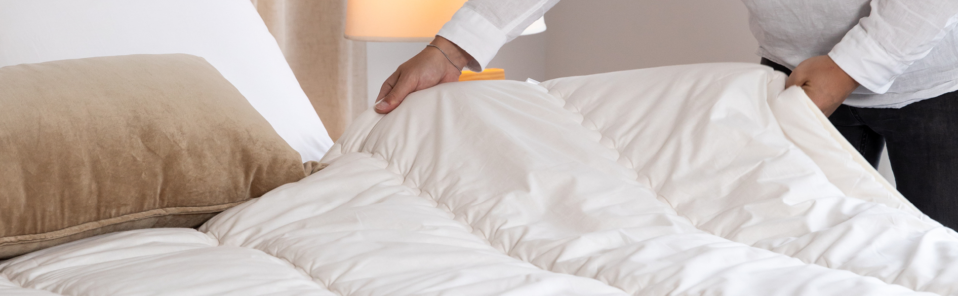 Rustig opgemaakt bed met wollen dekbed, natuurlijk licht en zachte tinten