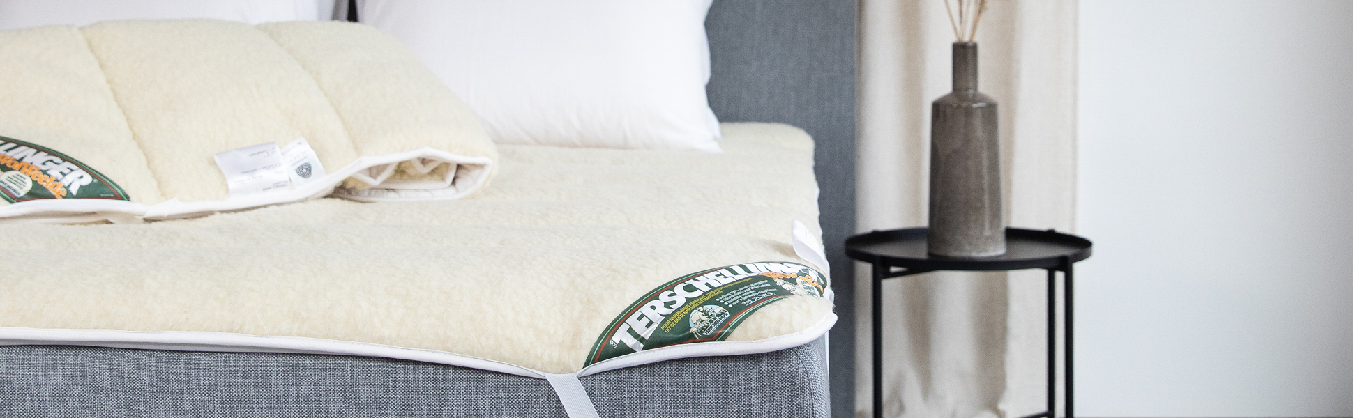 Wollen onderdeken op een matras met rustige styling en focus op natuurlijke materialen